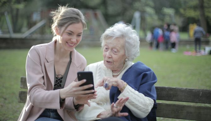 Une jeune femme et une vieille femme regardant un téléphone sur le banc